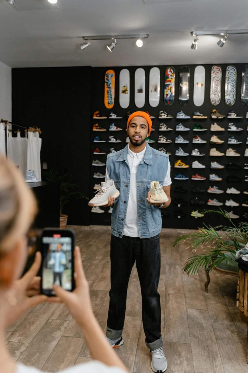 A Person Video Recording a Man in Denim Vest Holding a Pair of Rubber Shoes